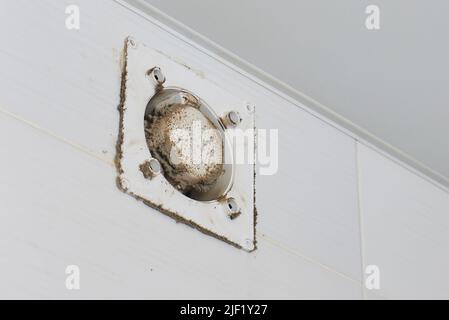 Un uomo pulisce la polvere da un tecnico della griglia di ventilazione pulendo l'aria Foto Stock