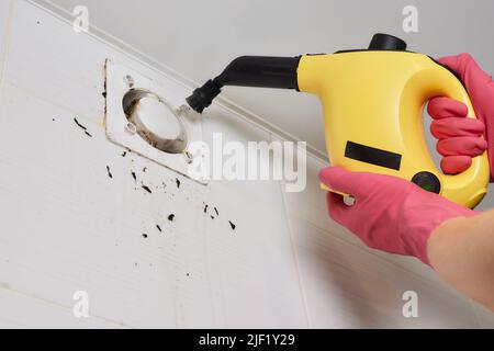 Un uomo pulisce la polvere da un tecnico della griglia di ventilazione pulendo l'aria Foto Stock