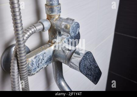 Un flusso sottile di acqua dura fluisce da un vecchio aeratore del rubinetto. Vecchio bagno rubinetto di sink contaminato con calcio e sporcizia Foto Stock