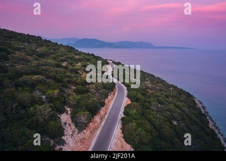 Vista aerea della strada vicino al mare blu, foresta al tramonto in estate Foto Stock
