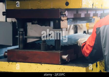 Processo di formatura della lamiera su pressa in fabbrica. Foto Stock