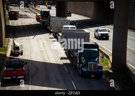 Carrelli che trasportano componenti in calcestruzzo prefuso a volta parcheggiati in linea su una carreggiata sotto un passaggio di revisione. Foto Stock