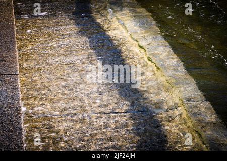 Piccole onde si avvolgono su gradini di pietra che entrano nell'acqua lungo il lungomare di Halifax, Nuova Scozia, Canada. Foto Stock
