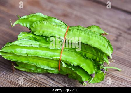 Fagiolo alato su sfondo ligneo, Psofocarpus tetragonolobus - fagiolo alare verde o fagiolo a quattro angoli Foto Stock