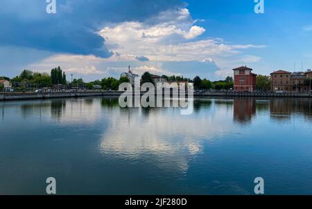 Ravenna, Italia: 10-04-2022: Splendidi edifici riflessi sulla darsena di Ravenna in una giornata di sole mattutina. Un molo è un'area coperta d'acqua per la quale viene utilizzata Foto Stock