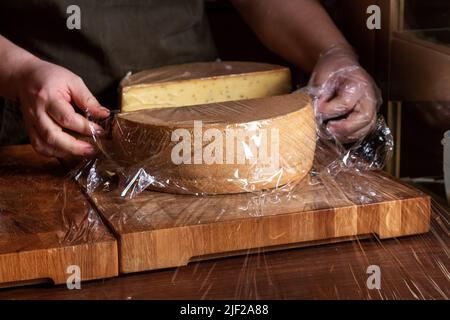 Un pezzo di formaggio viene confezionato sul banco. Foto Stock