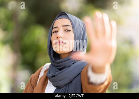 Donna musulmana seria che gesturing si ferma con la mano Foto Stock