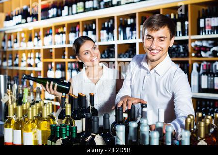 Ritratto di clienti maschi e femmine che raccolgono una bottiglia di vino Foto Stock