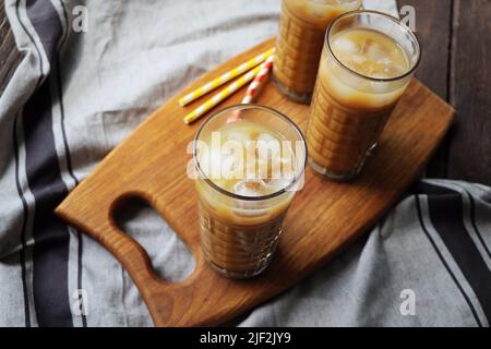 D'estate, sorseggiate un caffè ghiacciato in un bicchiere alto su un rustico sfondo di legno. Messa a fuoco selettiva Foto Stock