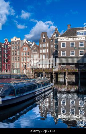 Splendidi vecchi magazzini, negozi e appartamenti lungo i canali iconici di Amsterdam. Girato in una serata estiva soleggiato con cielo blu profondo. Foto Stock