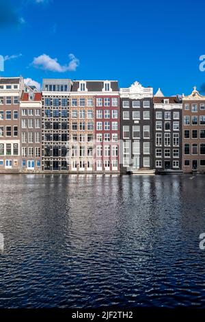 Splendidi vecchi magazzini, negozi e appartamenti lungo i canali iconici di Amsterdam. Girato in una serata estiva soleggiato con cielo blu profondo. Foto Stock