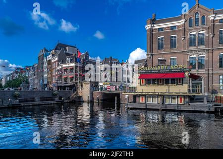 Splendidi vecchi magazzini, negozi e appartamenti lungo i canali iconici di Amsterdam. Girato in una serata estiva soleggiato con cielo blu profondo. Foto Stock