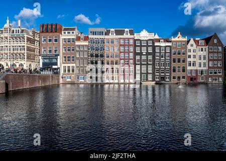 Splendidi vecchi magazzini, negozi e appartamenti lungo i canali iconici di Amsterdam. Girato in una serata estiva soleggiato con cielo blu profondo. Foto Stock