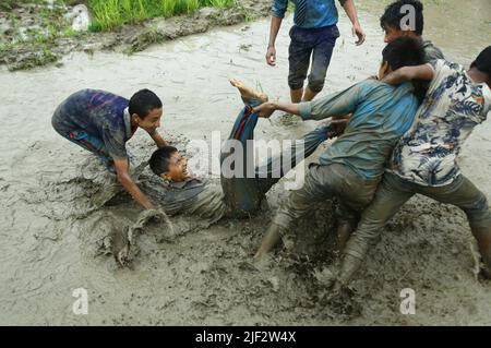 Kathmandu, Nepal. 29th giugno 2022. Gli studenti giocano nel fango mentre piantano campionamenti di riso sul campo durante il National Paddy Day, chiamato anche Asar Pandra, che segna l'inizio della coltivazione di riso piantando in risaie quando arriva la stagione monsonica, a Kathmandu, Nepal, 29 giugno 2022. (Credit Image: © Dipen Shrestha/ZUMA Press Wire) Foto Stock