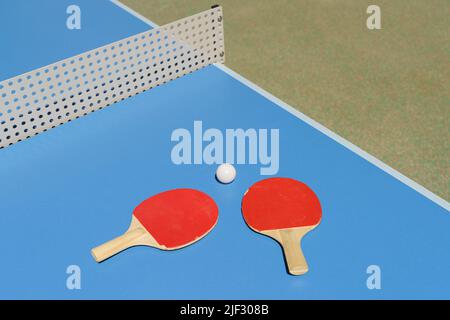 Ping pong tennis sfondo tavolo. Racchette da tennis e una palla su un tavolo da sport blu. Foto di alta qualità Foto Stock