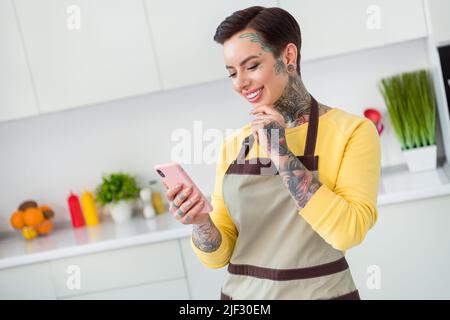 Ritratto di ragazza allegra attraente usando dispositivo ricetta di ricerca culinaria chatting fare pasto fresco in casa cucina al chiuso Foto Stock