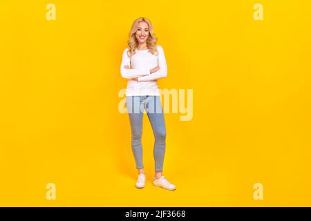 Foto di bella millenaria bionda donna incrociate braccia indossare camicia jeans scarpe isolate su sfondo giallo Foto Stock