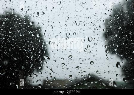 Fuoco selettivo delle goccioline d'acqua piovana sulla finestra di vetro della casa. Sfondo stagione piovosa. Foto Stock
