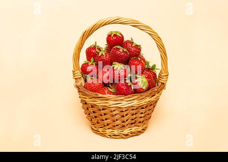 Cestino pieno di fragole isolato su sfondo beige. Foto Stock