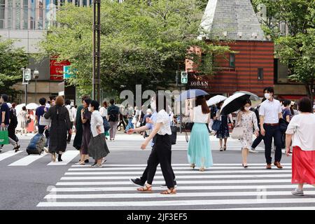 Le persone che usano Sukiyabashi di Ginza corrono in una giornata calda. Una cassetta di polizia, un koban e un centro commerciale sono sullo sfondo. Foto Stock