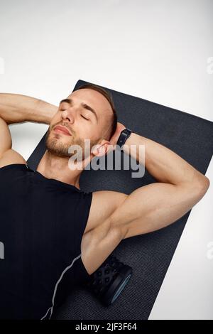 Man Foam Rolling. L'atleta si allunga utilizzando un rullo in schiuma. Foto Stock