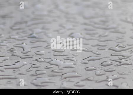 Molte gocce di pioggia su una superficie del tavolo in giorno piovoso mostrano le perle dell'acqua come disegno lucido astratto per rappresentare i giorni piovosi e il giorno di pioggia del tempo di autunno Foto Stock