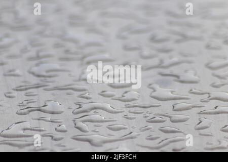 Molte gocce di pioggia su una superficie del tavolo in giorno piovoso mostrano le perle dell'acqua come disegno lucido astratto per rappresentare i giorni piovosi e il giorno di pioggia del tempo di autunno Foto Stock
