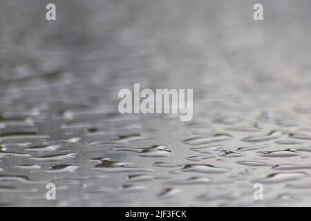 Molte gocce di pioggia su una superficie del tavolo in giorno piovoso mostrano le perle dell'acqua come disegno lucido astratto per rappresentare i giorni piovosi e il giorno di pioggia del tempo di autunno Foto Stock