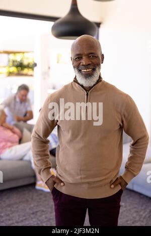 Ritratto di sorridente anziano afro-americano con le mani in tasche in piedi in casa di cura Foto Stock