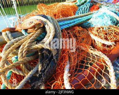 Linee di ormeggio gialle, arrugginite e blu. Reti da pesca, industria della pesca, vecchia corda e arrugginito sistema di carrucole in metallo parte sulla barca da pesca Foto Stock