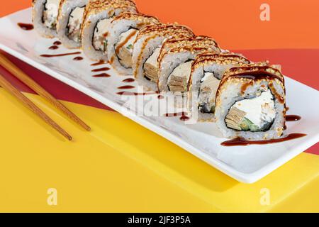 Il sushi di nigiri sets, Uramaki, California, Philadelphia, su un piatto bianco. Vicino a zenzero e wasabi. Salsa di soia in un recipiente bianco. Su sfondo colorato. Co Foto Stock