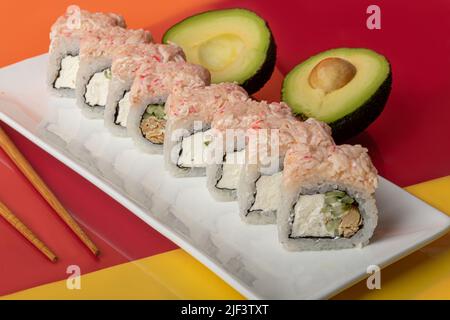 Il sushi di nigiri sets, Uramaki, California, Philadelphia, su un piatto bianco. Vicino a zenzero e wasabi. Salsa di soia in un recipiente bianco. Su sfondo colorato. Co Foto Stock