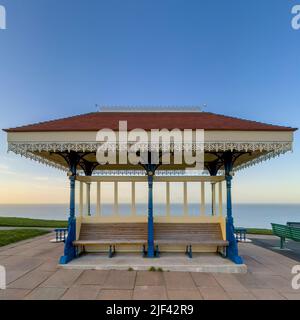 Panchine in legno in un rifugio Victoria sul North Terrace a Whitby, con il Mare del Nord in lontananza. REGNO UNITO Foto Stock