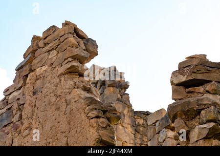 rovine di antiche mura di pietra contro un cielo nuvoloso Foto Stock