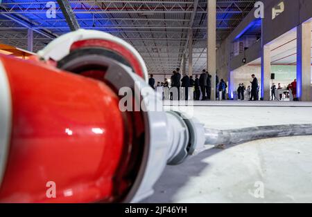 Schkeuditz, Germania. 29th giugno 2022. Gli ospiti della cerimonia di consegna per una nuova sala logistica presso l'aeroporto di Lipsia/Halle seguono i discorsi nella conchiglia della sala. La società Mitheresa, con sede a Monaco di Baviera, è una piattaforma online per la moda di lusso e sta costruendo un nuovo e moderno edificio logistico che copre circa 55.000 metri quadri a Schkeuditz, direttamente all'aeroporto. I primi 500 dipendenti dovrebbero iniziare a lavorare presso il centro logistico a metà del 2023. In totale, oltre 1.000 posti di lavoro saranno creati nel sito entro il 2030. Credit: Hendrik Schmidt/dpa/Alamy Live News Foto Stock