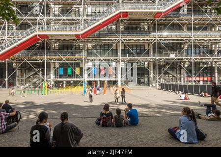 Turisti seduti sulla piazza di fronte al Centro Georges Pompidou, Place Georges Pompidou, Beaubourg. Parigi, Francia. Foto Stock