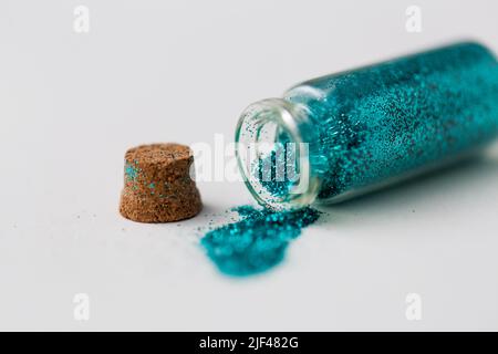 luccichia blu versata da una piccola bottiglia di vetro Foto Stock