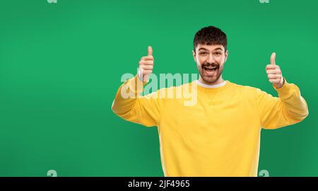 l'uomo felice mostra i pollici su sfondo verde Foto Stock