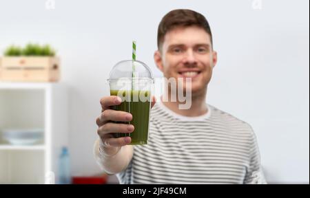 uomo che beve frullato verde da tazza usa e getta Foto Stock