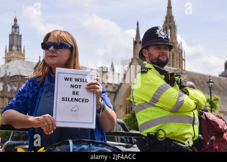Londra, Regno Unito. 29th giugno 2022. Un manifestante ha un cartello con la dicitura "non saremo tacitati” accanto a un ufficiale di polizia. I dimostranti si sono riuniti in Piazza del Parlamento in solidarietà con l'attivista anti-Brexit Steve Bray il giorno dopo che ha fatto il suo sistema sonoro sequestrato dalla polizia, mentre la polizia, la criminalità, la condanna e la giustizia Bill sono entrate in vigore nel Regno Unito, limitando le proteste 'rumorose' e protestando contro le restrizioni. I manifestanti hanno suonato musica ad alto volume su un nuovo sistema audio. Credit: Vuk Valcic/Alamy Live News Foto Stock