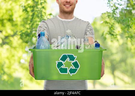 sorridente giovane uomo smistando rifiuti di plastica Foto Stock