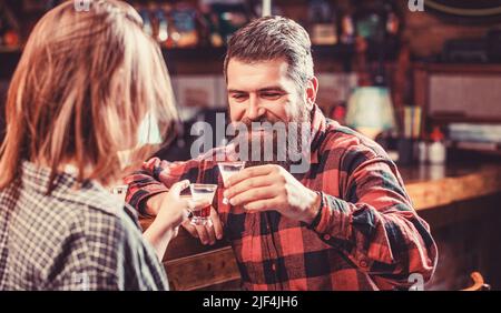 Bevanda alcolica femminile al bar. La giovane donna ha problemi con l'alcol. Alcolismo maschile femminile. Giovane uomo che beve alcol Foto Stock
