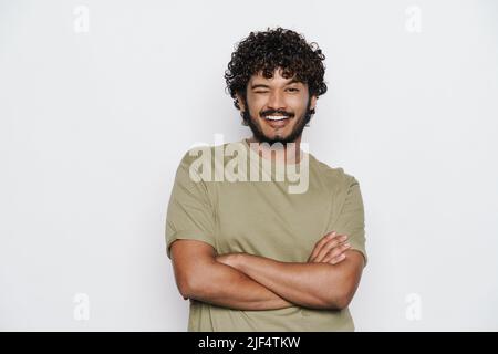 Giovane uomo bearded vestito in t-shirt winking e sorridente a macchina fotografica isolato su sfondo bianco Foto Stock