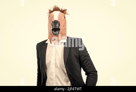 L'uomo professionista indossa la testa di cavallo e il vestito da lavoro isolato su cavallo bianco Foto Stock