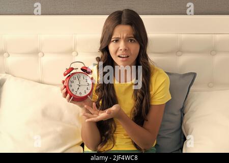 La ragazza infelice si lamenta della sveglia a letto, ora del mattino Foto Stock