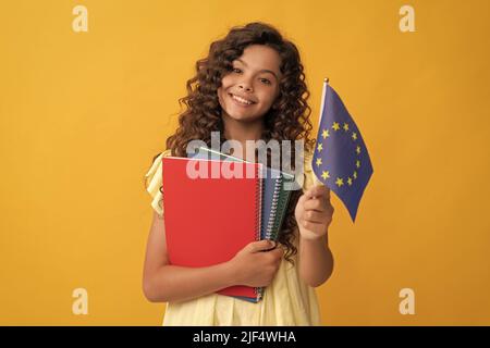 felice adolescente studia con i libri di lavoro della scuola detengono la bandiera dell'unione europea, visto schengen Foto Stock