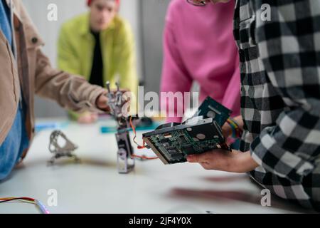 Bambini con insegnante che lavorano insieme al progetto con giocattoli elettrici e robot in aula di robotica, primo piano Foto Stock