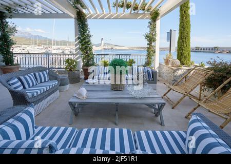 Interno del ristorante all'aperto con cuscini a righe e vista sul mare. Foto Stock