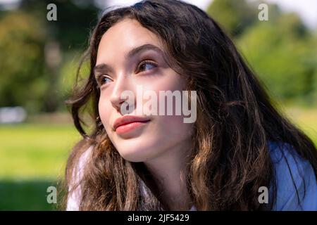 Ritratto di giovane donna che posa prono su erba in un parco Foto Stock