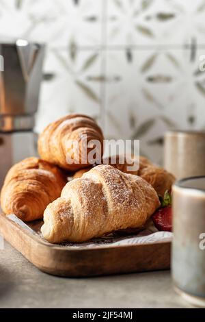 Croissant su vassoio di legno con frutti di bosco e caffè per la colazione con sfondo piastrellato. Orientamento verticale Foto Stock